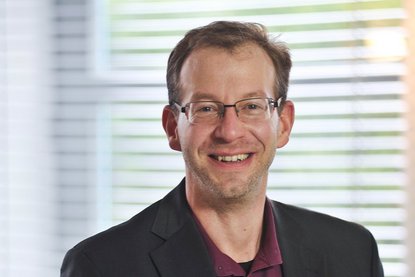 Ein Mann mit Brille lächelt in die Kamera - Im Hintergrund sieht man verschwommen eine Jalousie - Copyright: Ev.-Luth. Johann-Hinrich-Wichern-Kirchengemeinde zu Lübeck